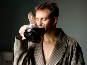 穿着睡衣的男人用咖啡壶喝咖啡